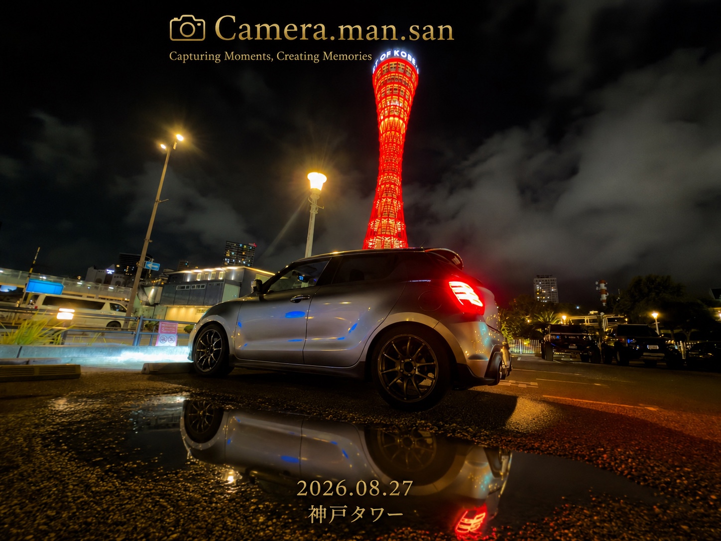 Car beside the illuminated Kobe Port Tower, reflected in wet pavement