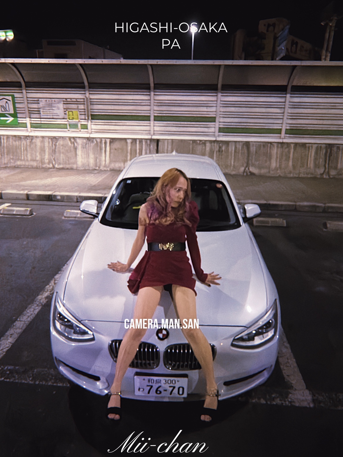 Portrait in a red dress in front of a white BMW at night